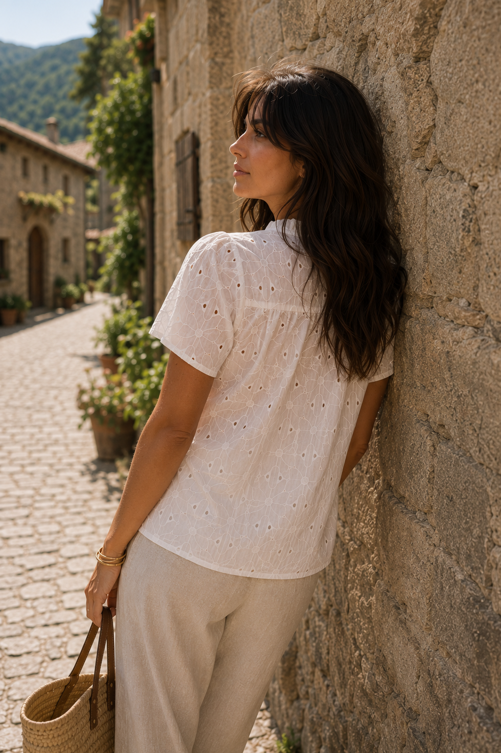 Vista trasera de blusa blanca bordada con canesú fruncido, combinada con pantalón fluido beige y capazo en un outfit effortless chic | STRANNA