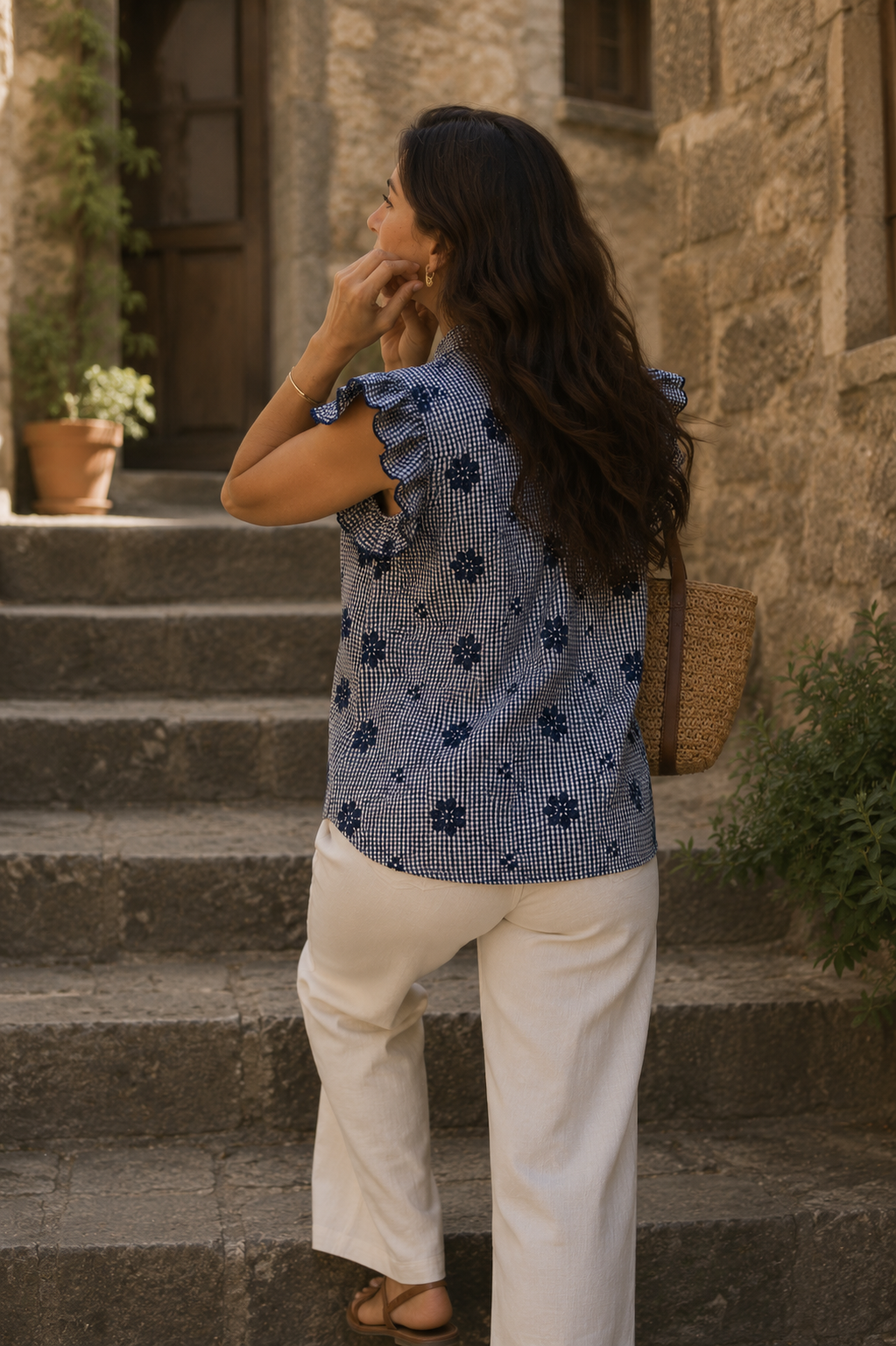 Vista trasera de blusa de cuadros vichy con bordados florales y volantes, llevada con pantalón blanco en un outfit de moda mediterránea mujer | STRANNA
